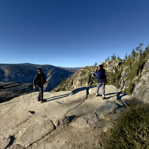 Family walking across granite with Yosemite views