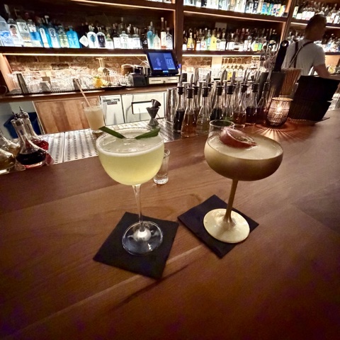 Two cocktails on a San Francisco bar with backlit shelves
